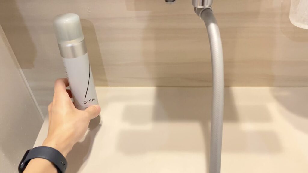 浴室にDISMのスプレー泡洗顔を置く男性